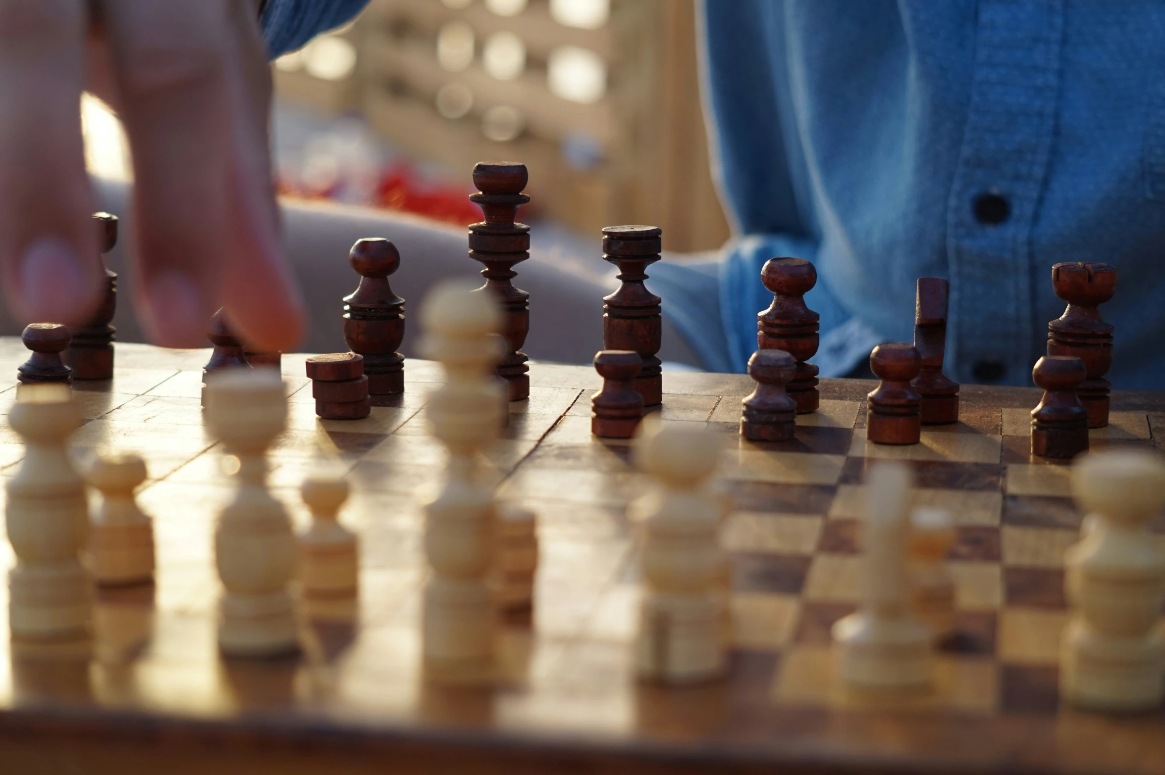 a person is playing with a wooden chess set