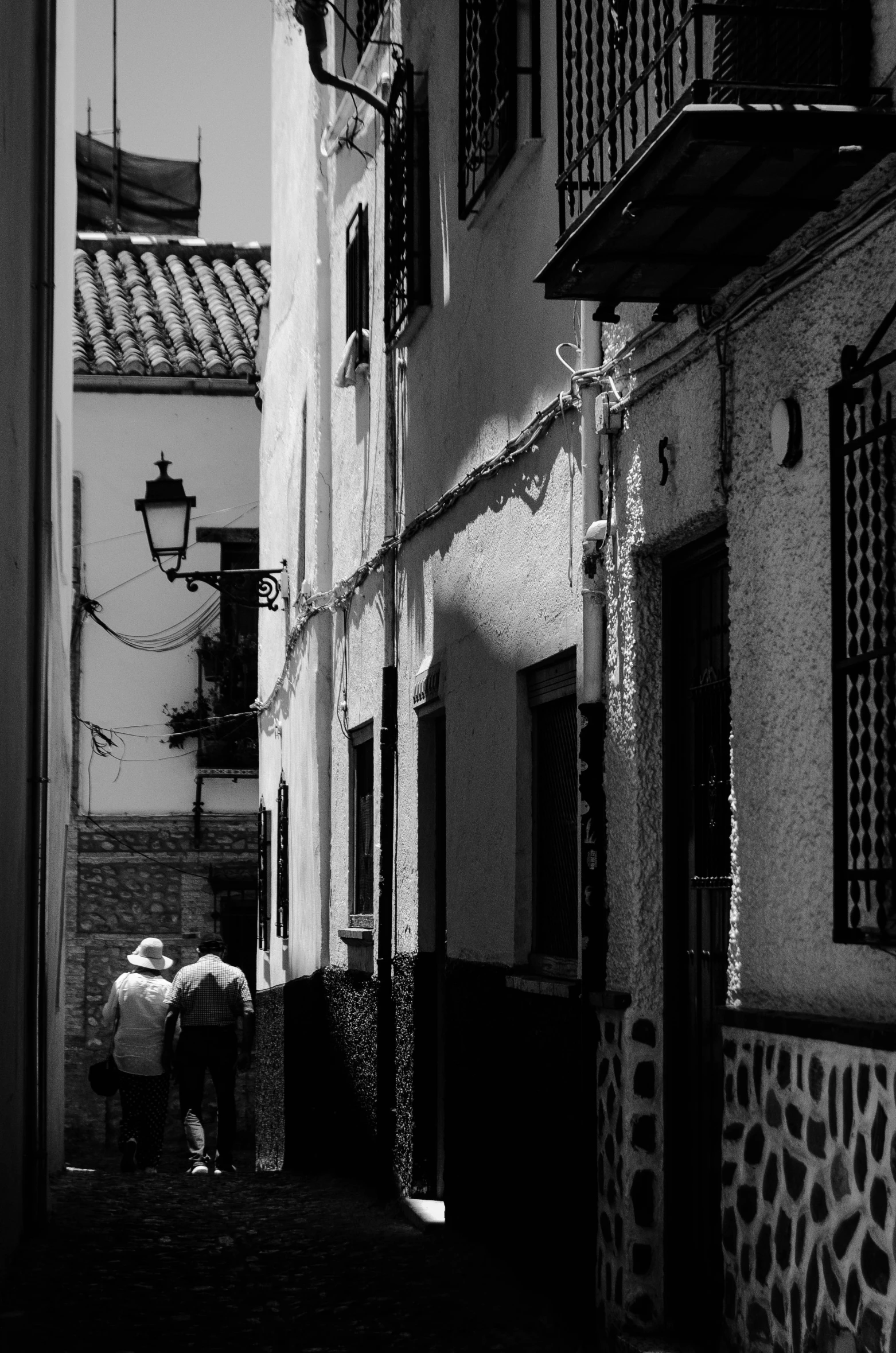 black and white pograph of people walking down a narrow street