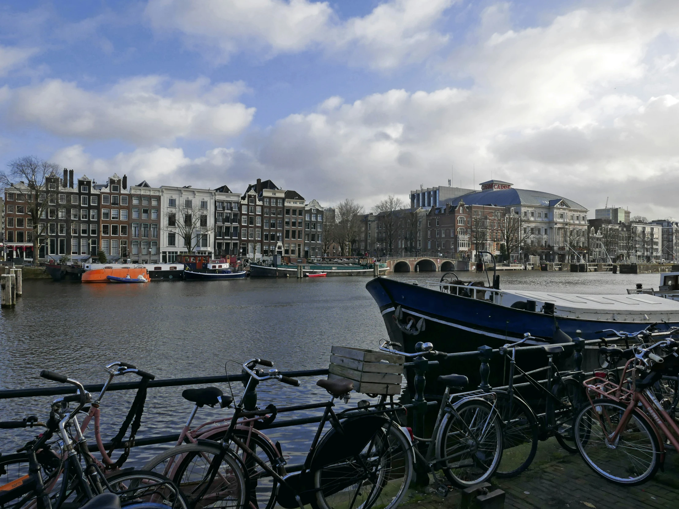 several bicycles parked next to the water near a city