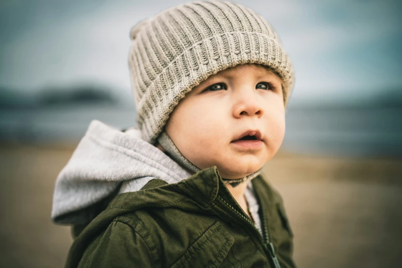 a small boy in a knit hat looks up