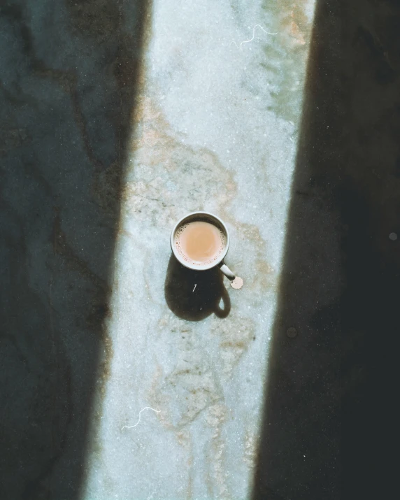 a coffee mug on a sidewalk looking down