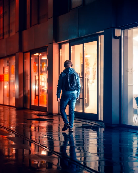 a man is walking in the rain at night