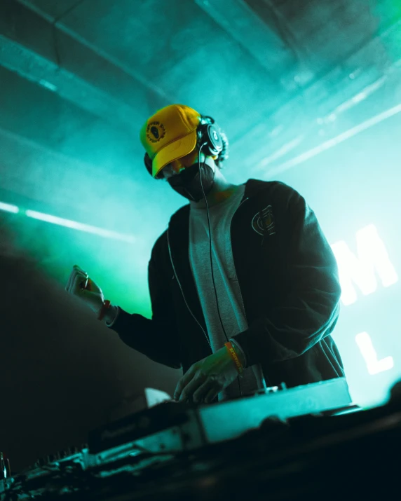 a dj in a yellow hat mixing at a concert