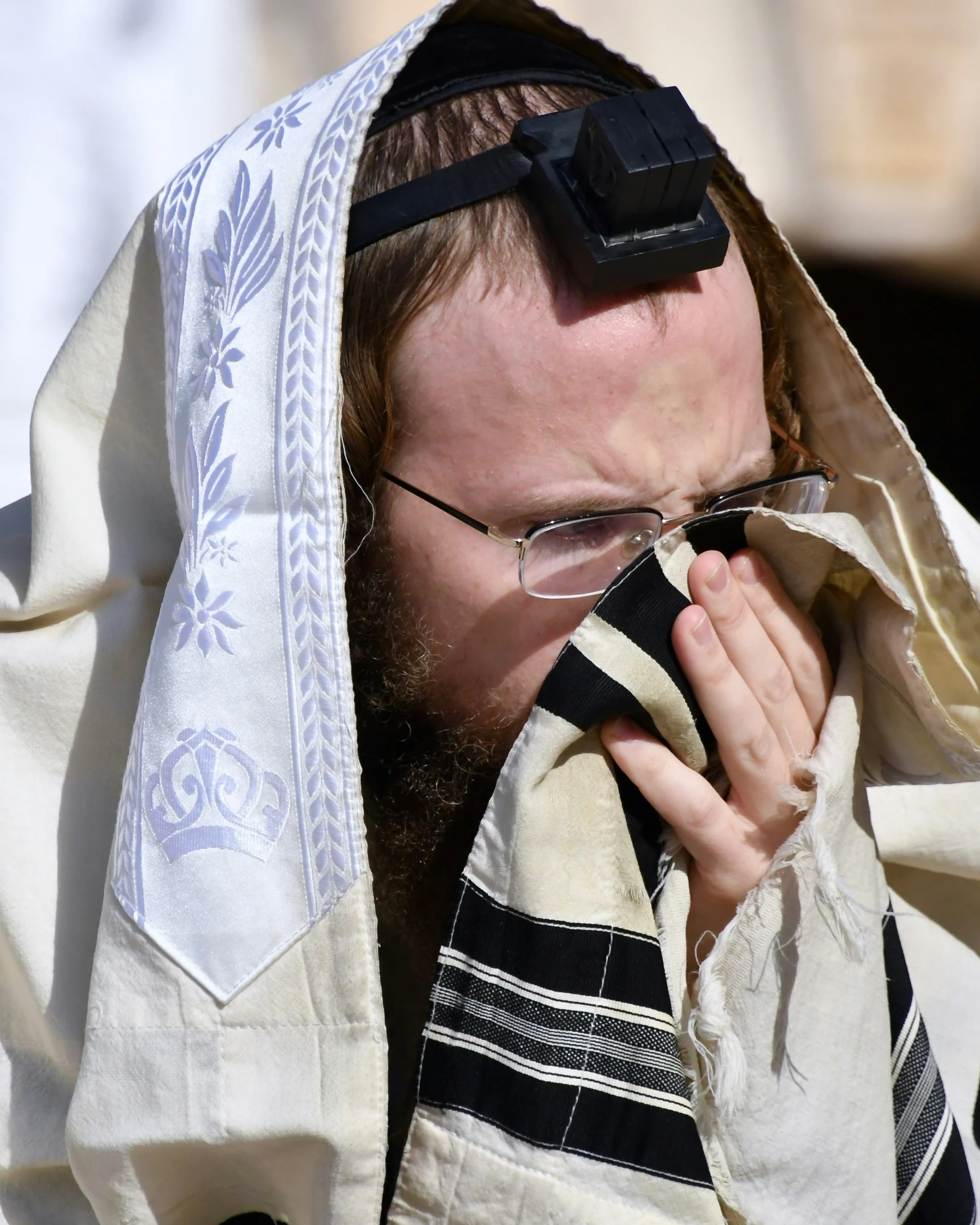 a man with a priest robes covers his eyes