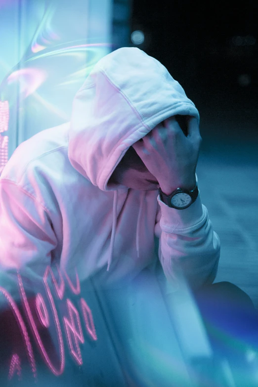 a person sitting on the sidewalk and wearing a hoodie