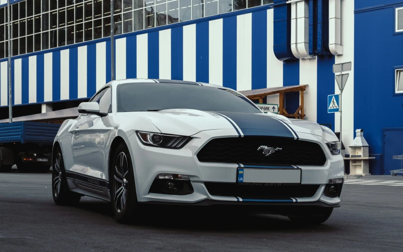 a silver mustang car sits on the side of the road near a loading dock