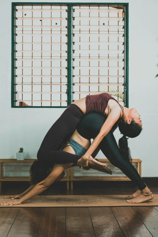 two people are doing yoga exercises on a wooden bench