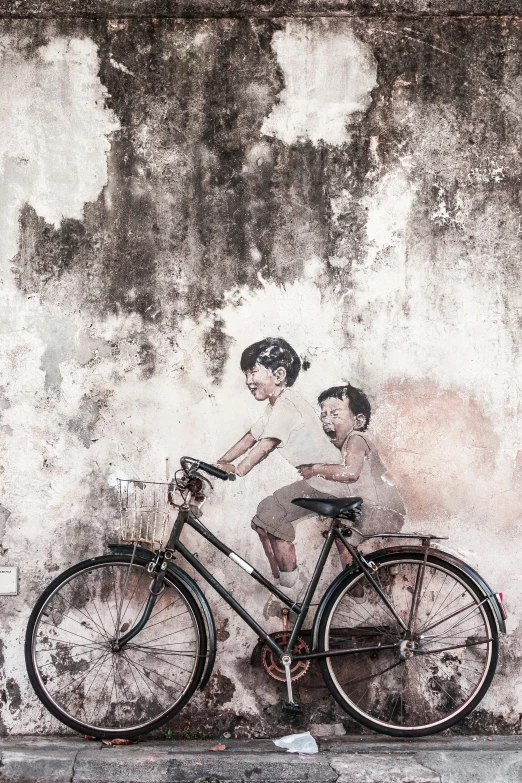 a painting of two children on a bike painted on the side of a building