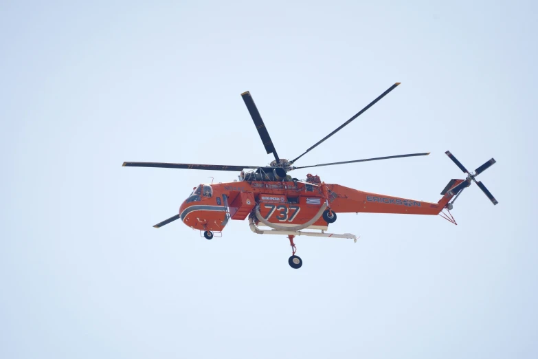 a red helicopter flying through the air on a clear day