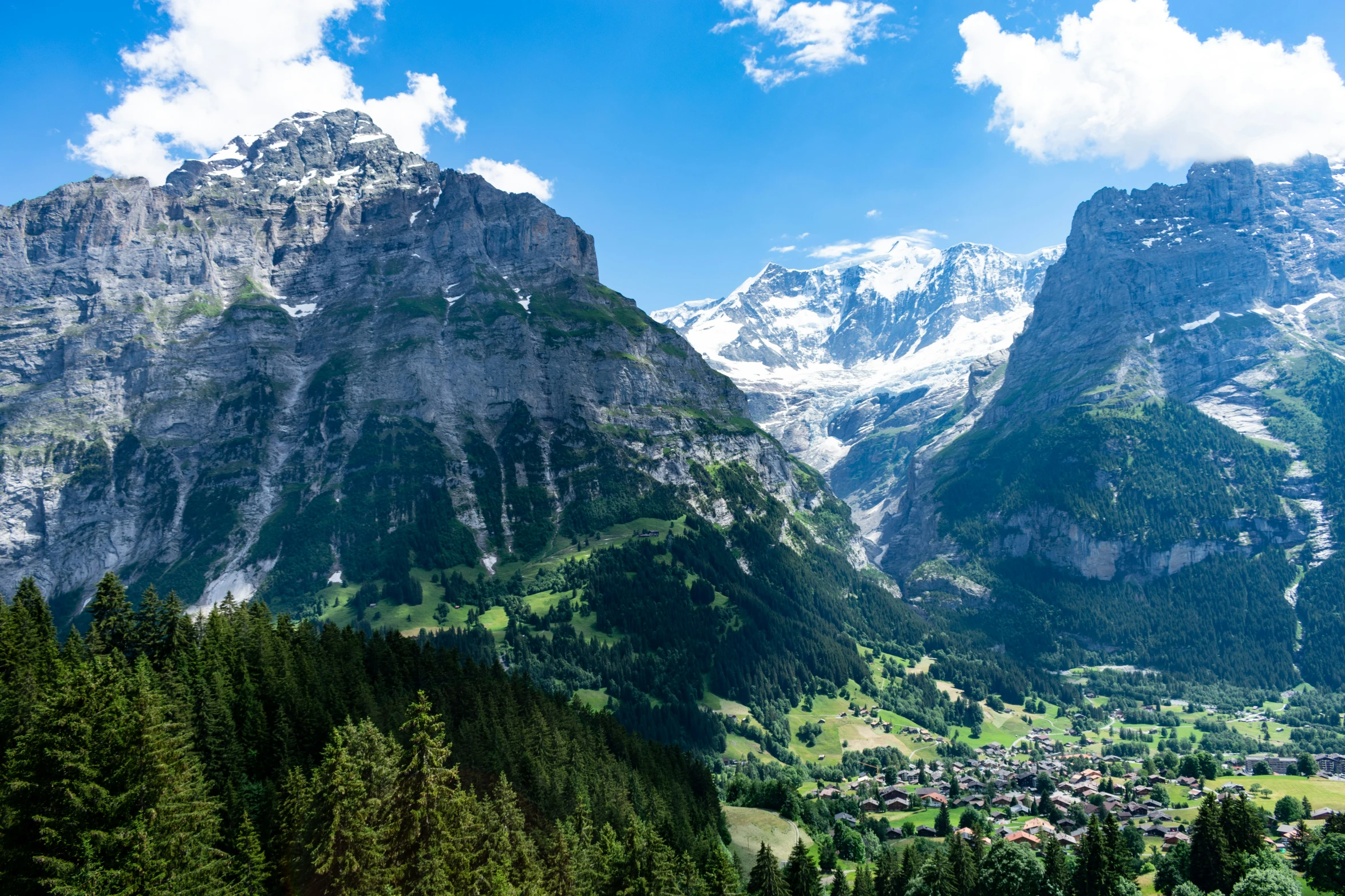 a mountain with a village nestled between some green trees