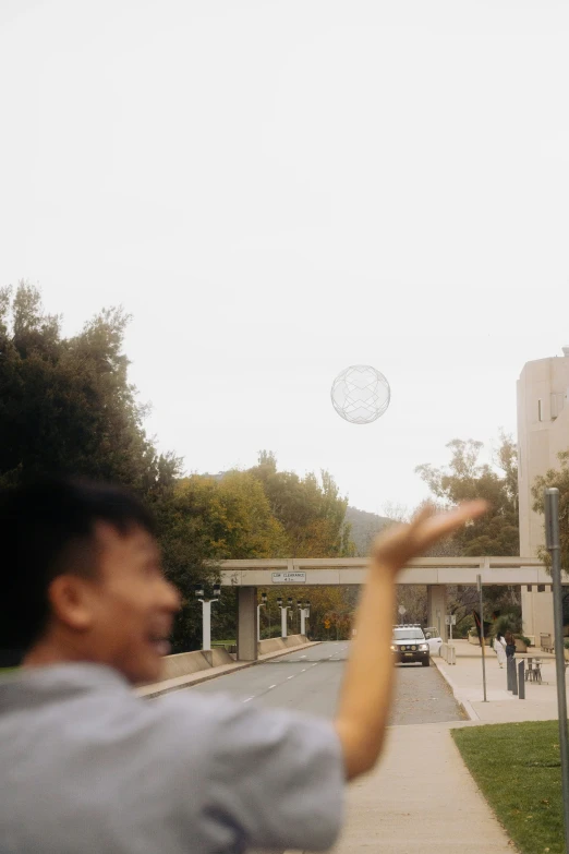 man throwing a ball in the air on the street