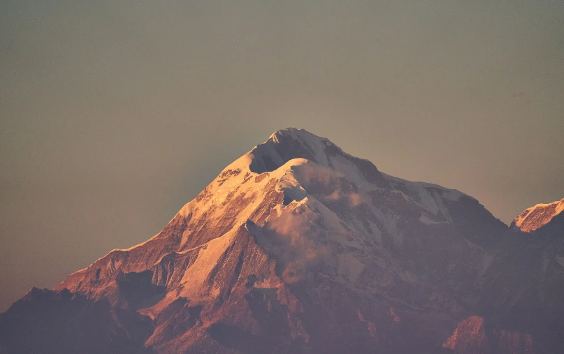 a snowy mountain with the sun shining on it