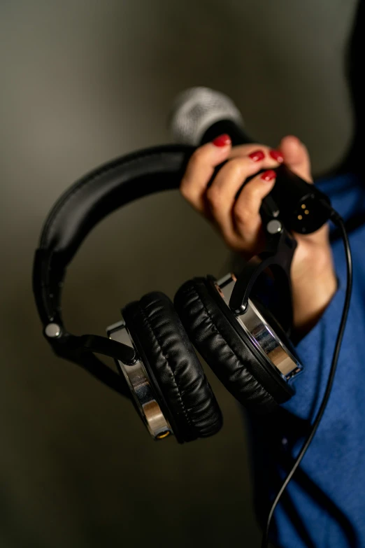 a woman with red nails holding up headphones and mp3