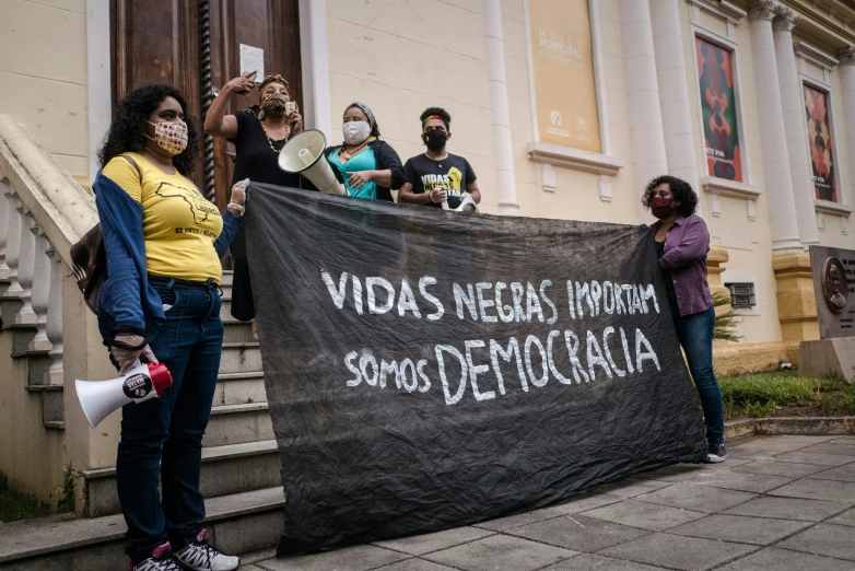 several people stand near a sign in a line