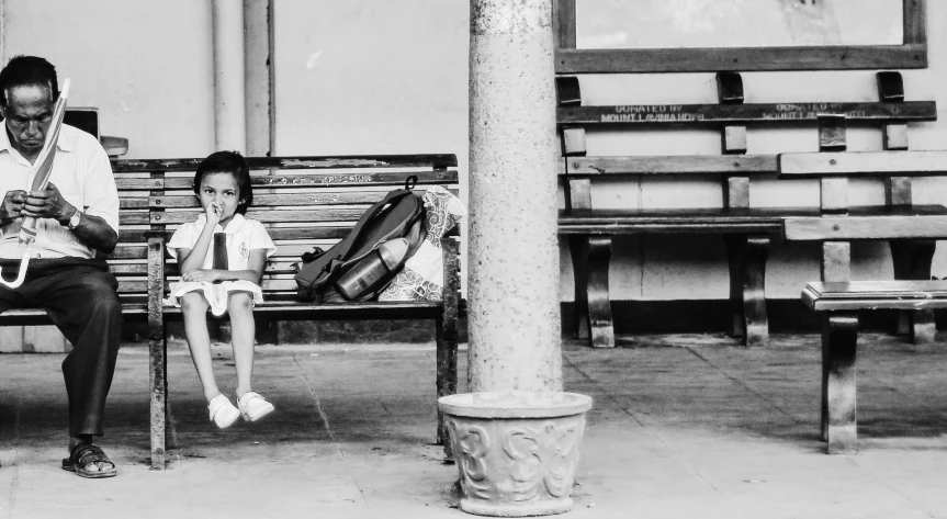 a man and a little girl sitting on a bench