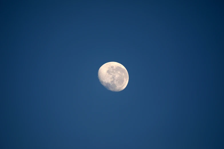 a full moon that is in the blue sky