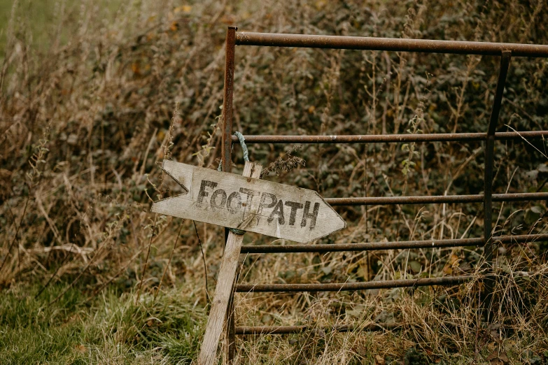 an old metal fence holds a worn road sign