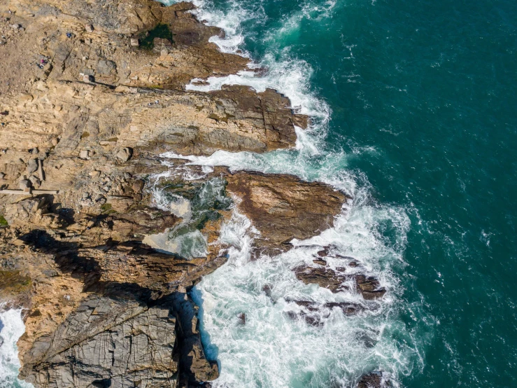 waves crash the rocky coast in front of some cliff formations