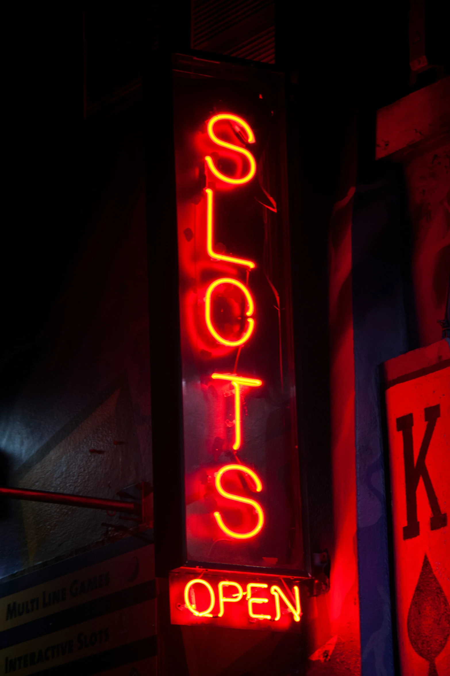 a red neon sign that reads slots is lit up