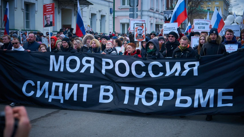 large groups of people holding a protest with russian flags