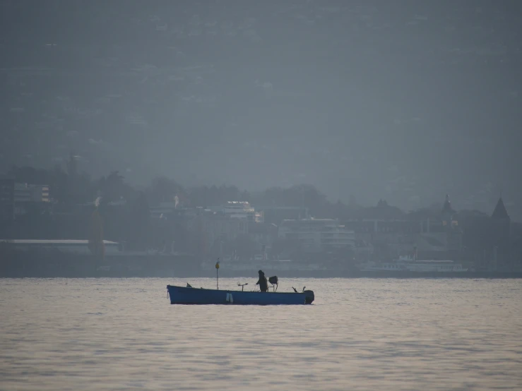 there is a man fishing on the lake in the fog