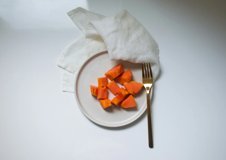 sliced up carrots on a white plate with a fork