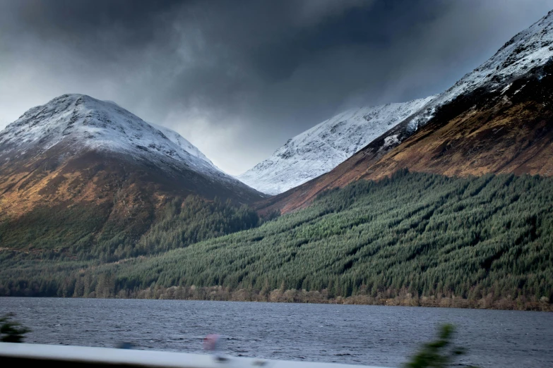 mountains are next to the water under storm clouds