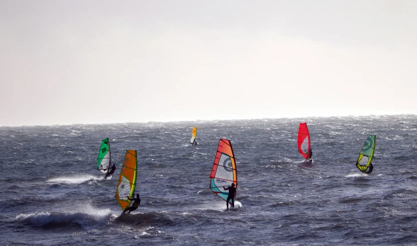 a group of people windsurfing in the ocean