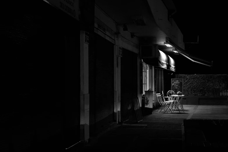 the shadows from an outside restaurant light illuminate the darkened street