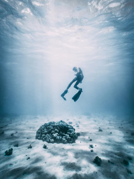 a person in scuba gear is floating above a rock