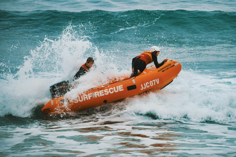 an orange raft is pulled into the waves as a man looks on