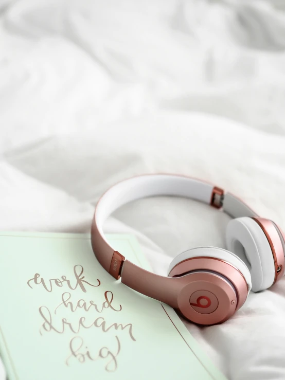 a note and headphones sitting on top of a bed