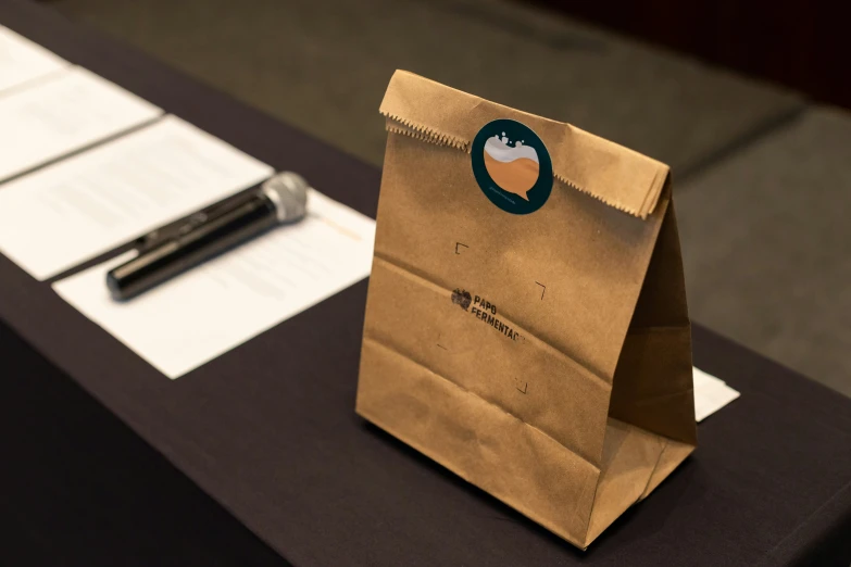 a brown bag on a table next to papers