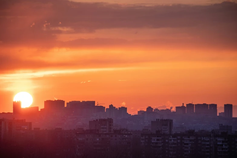 the sun setting over the city skyline, with building