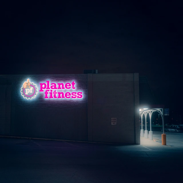 the neon sign for planet fitness has been lit up at night