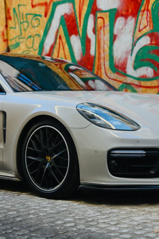 a white sports car with black rims parked near some graffiti