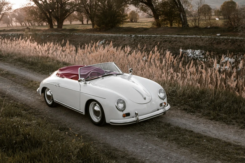 a classic sports car sitting on a dirt road