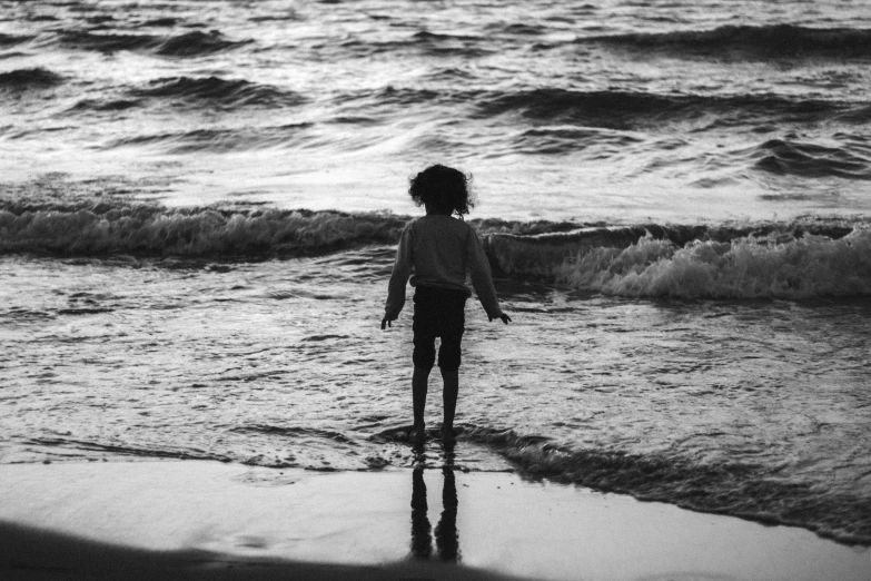 a young person standing in the water at a beach
