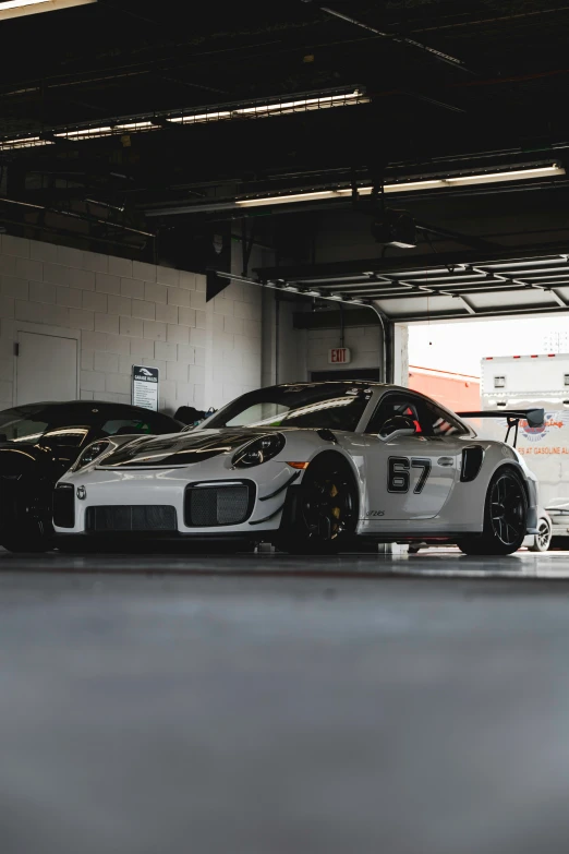 two racing cars in a garage one being black and white