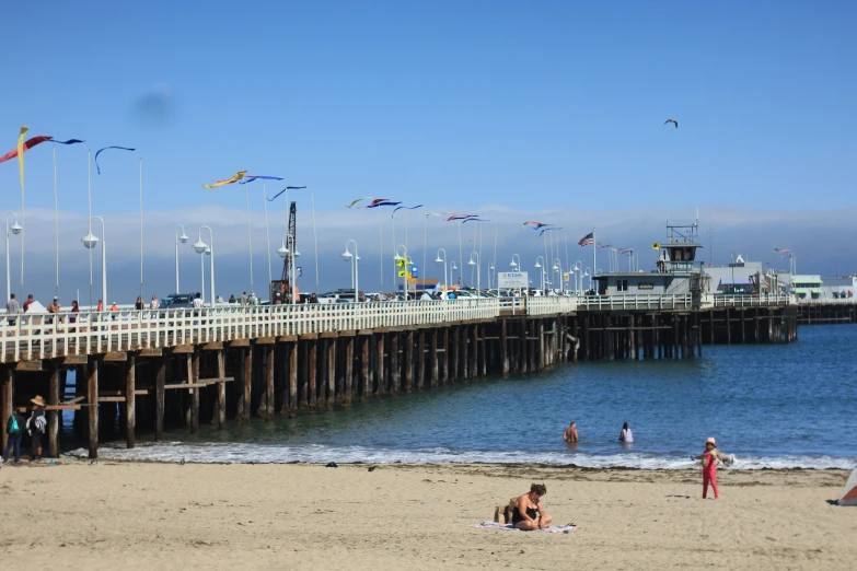 a pier that has people on it and kites flying in the sky
