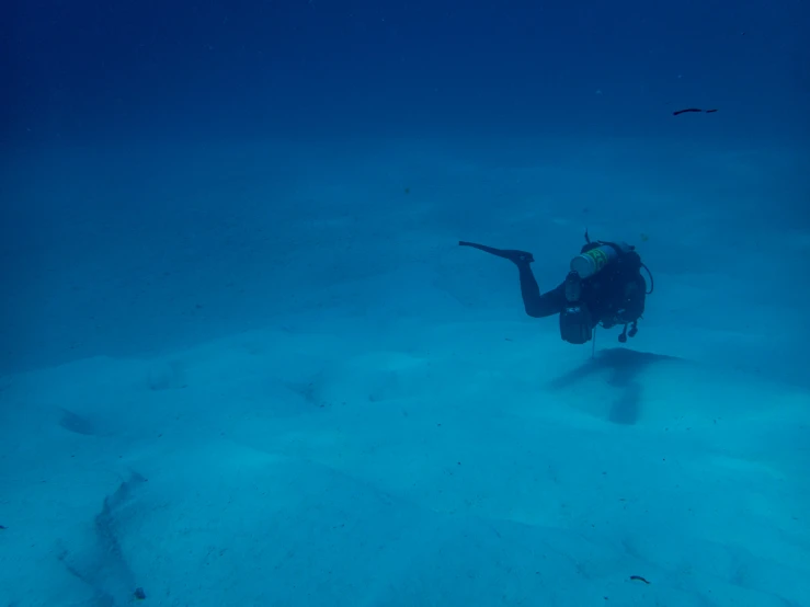 a person with a scuba suit diving in a deep blue sea