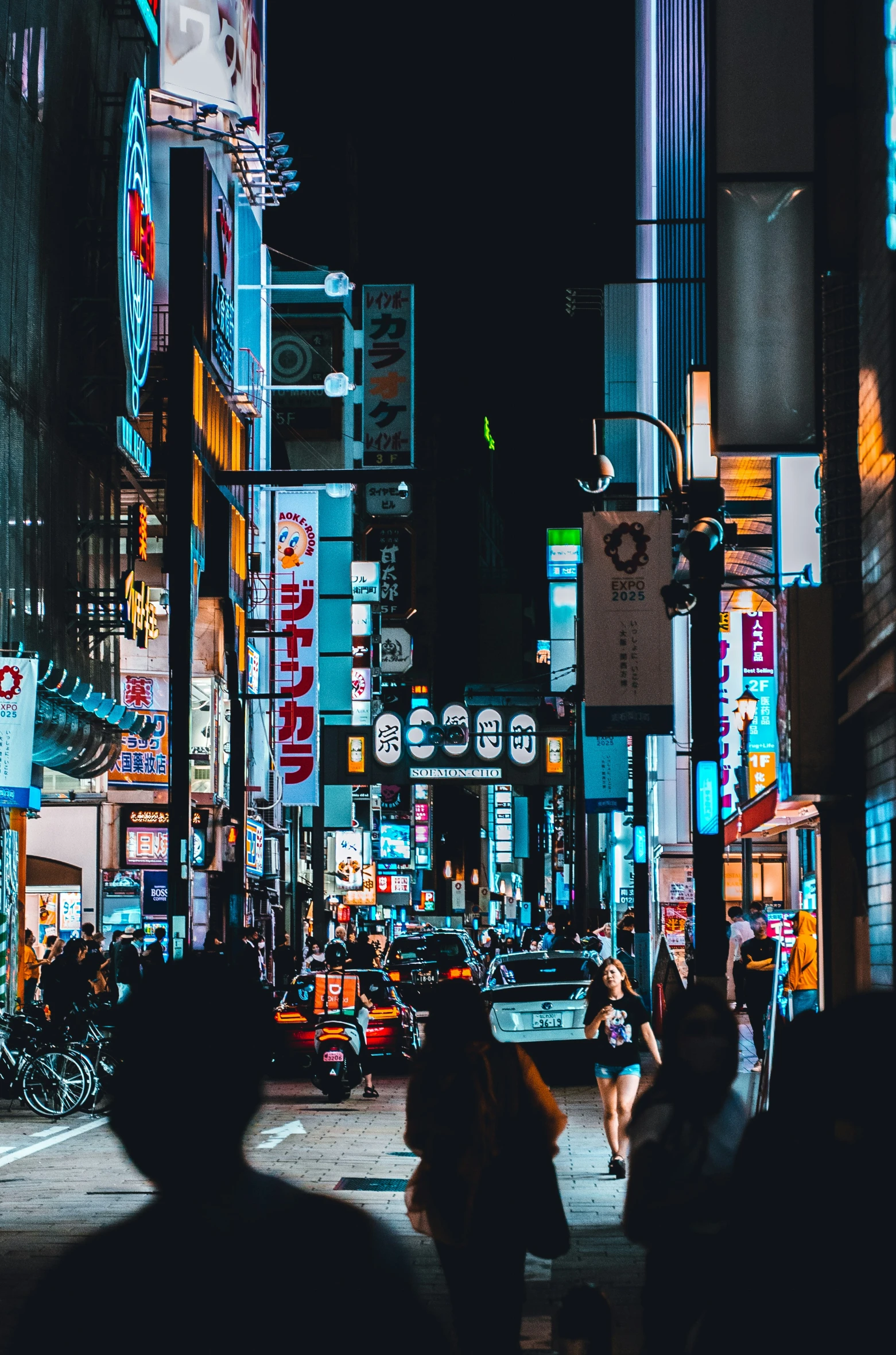 pedestrians walk down a city street at night
