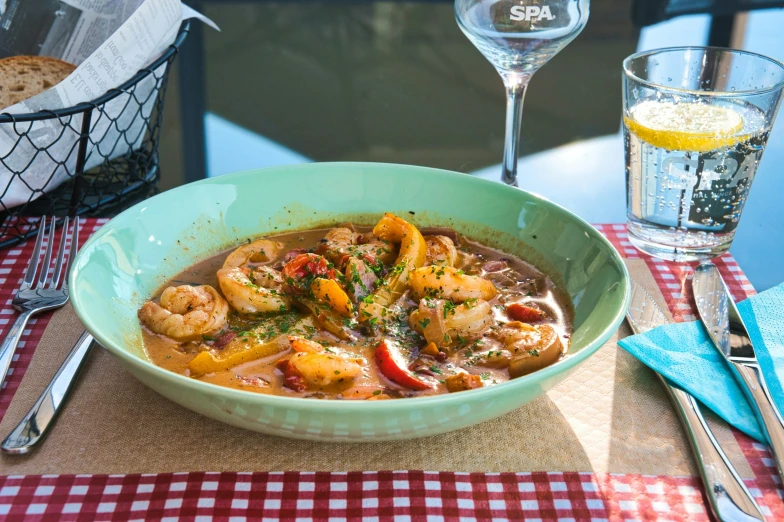 a bowl of soup with shrimp and peppers in a sauce