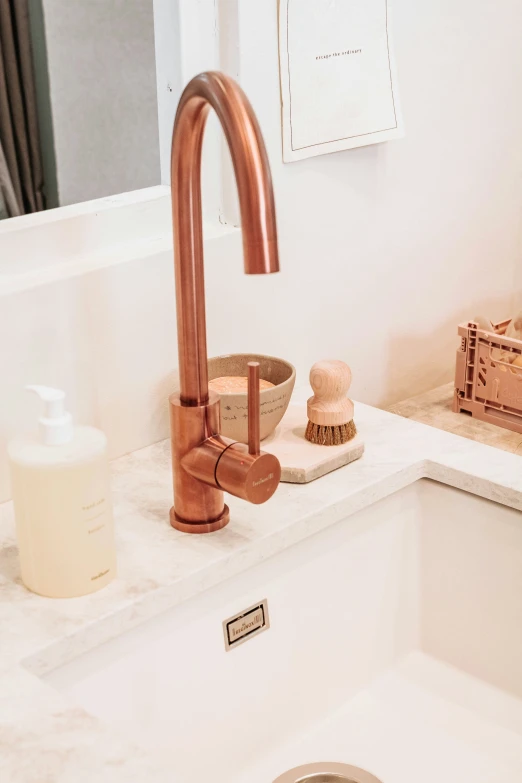 a white sink with copper faucet in a bathroom