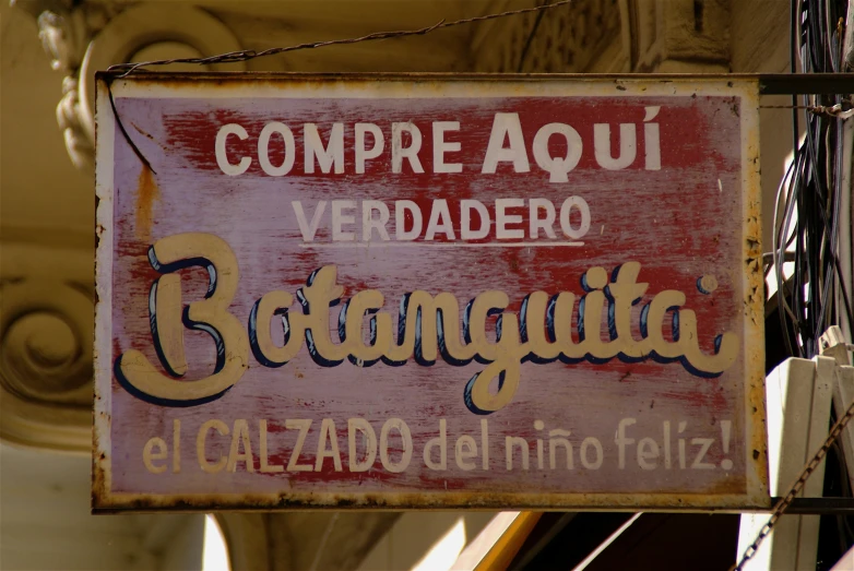 an old sign on a building hanging off the side