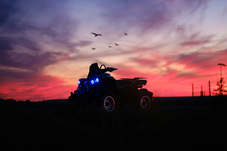 a quad bike at sunset with birds flying overhead