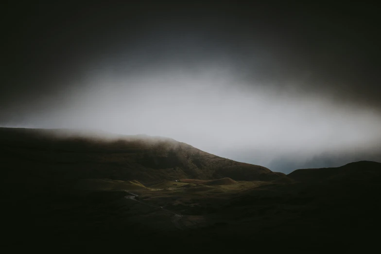 clouds on top of a hill covered in dark