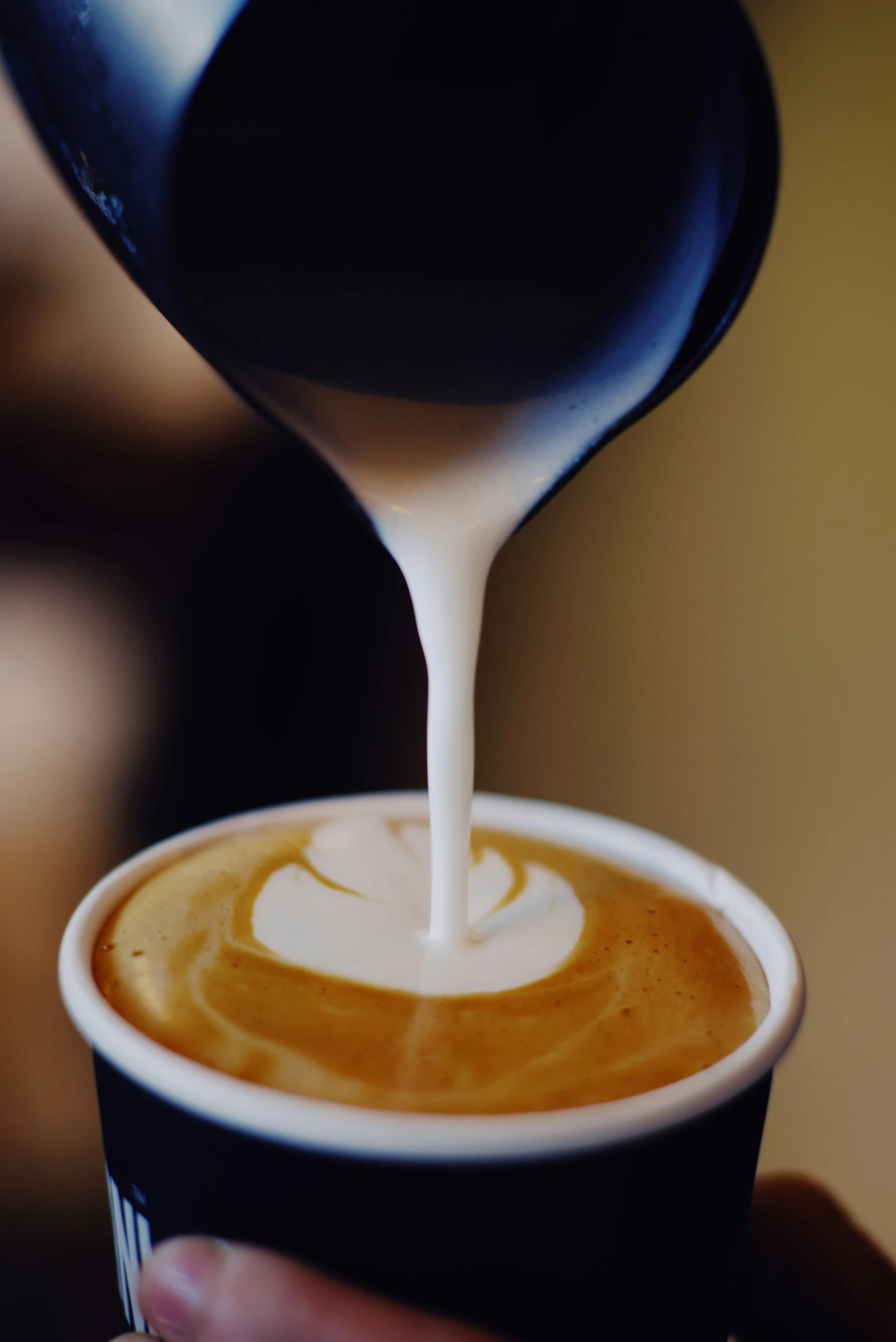 the liquid being poured into a cup of coffee