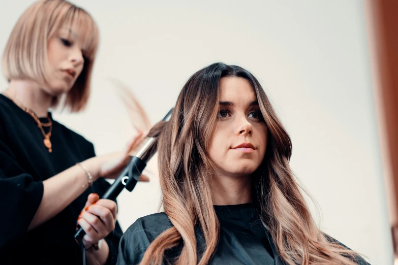 two women  their long hair at a hair salon