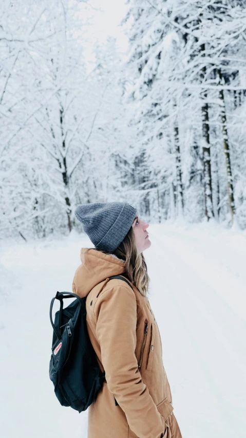 a woman walking through the snow in front of some trees